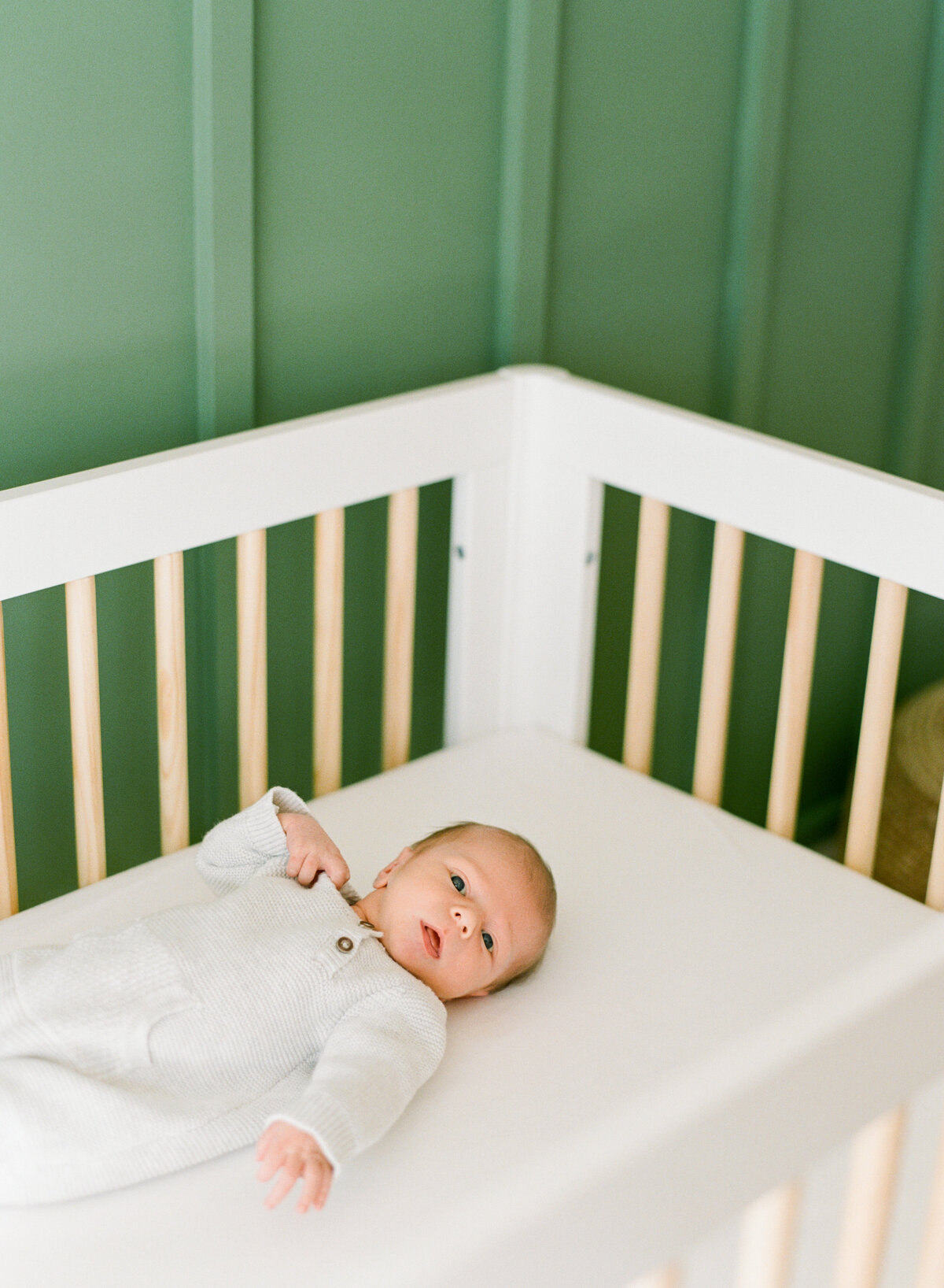 Baby lays in a crib wide awake during a newborn photography session in Raleigh. Photo by Raleigh Newborn Photography A.J. Dunlap Photography.