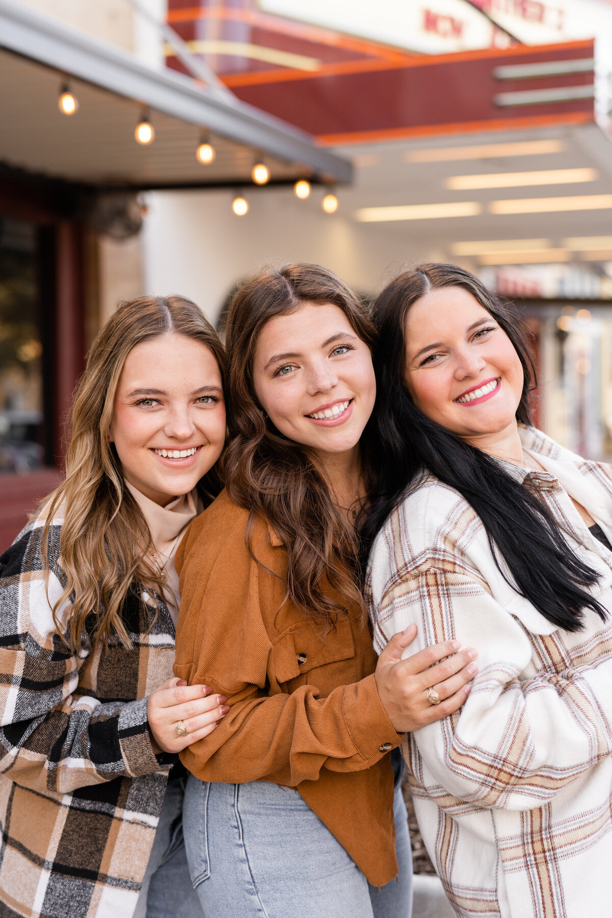 Senior girls in fall flannels hugging elbows and smiling in Downtown Bryan