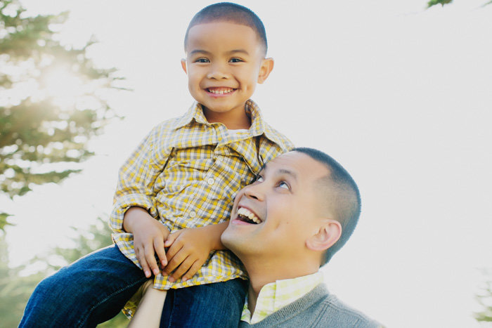 Portrait of a dad holding his kid up in the air smiling at the child