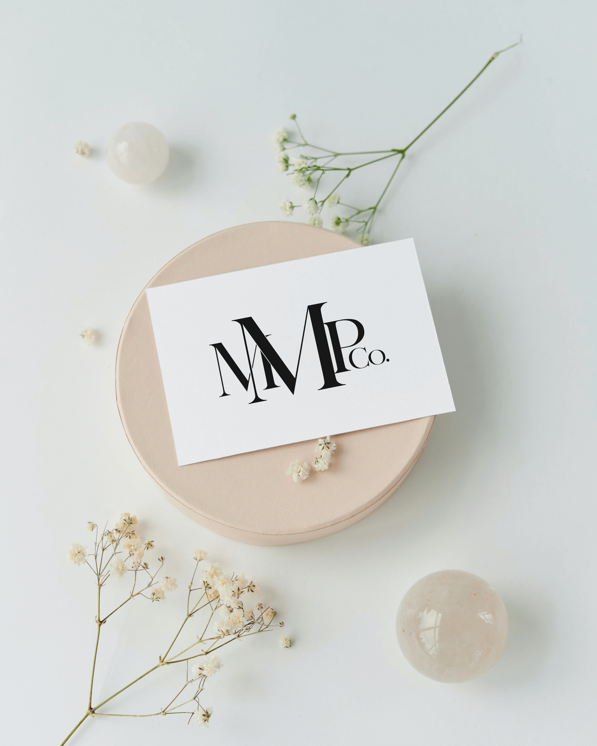 A brand logo for a photographer MMPCo. sits on a paper with florals and stationary