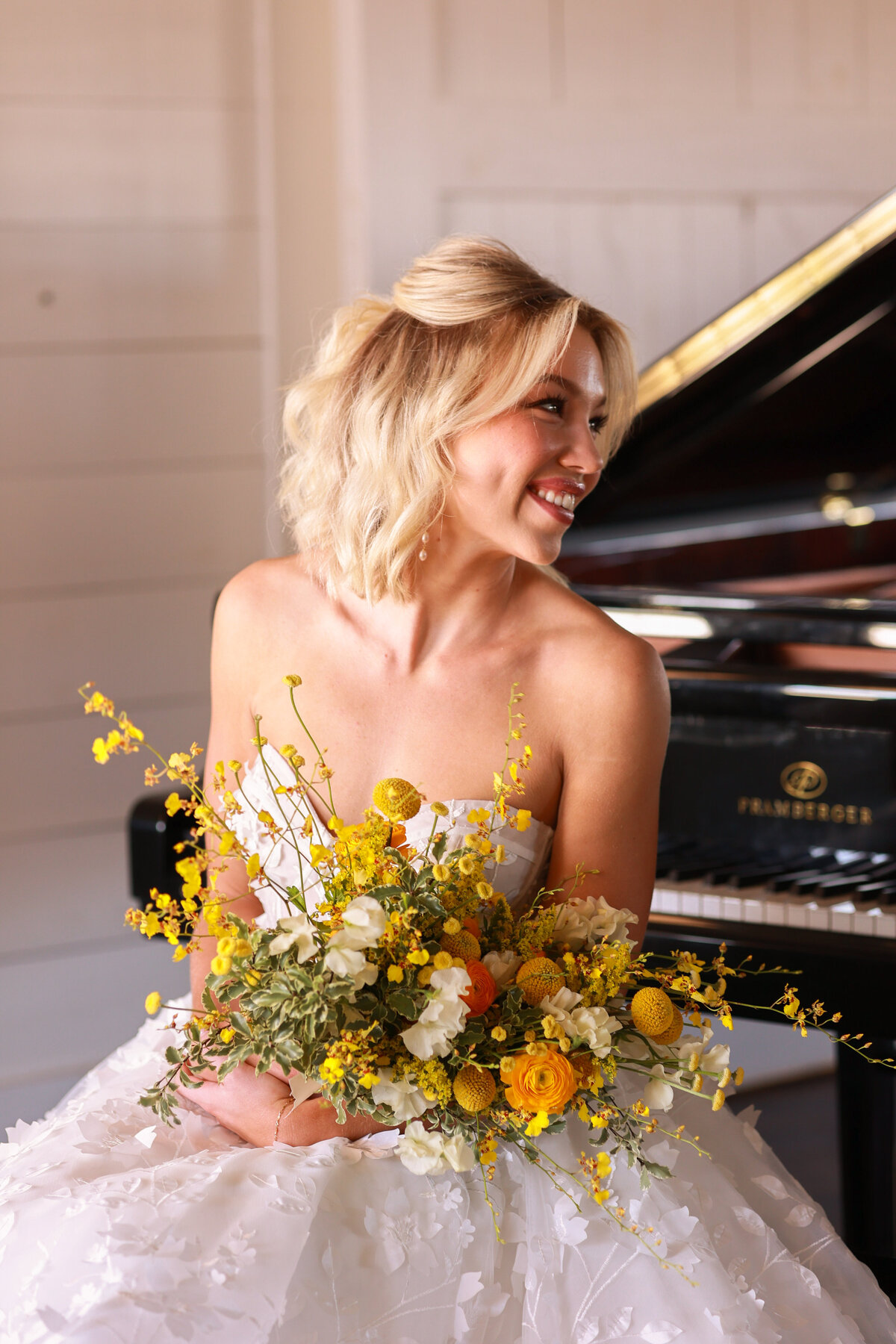 bride holding yellow bouquet sitting at grand piano at Hight Pointe Estate in Austin Texas by Austin Texas Wedding photographer Amanda Richardson Photography