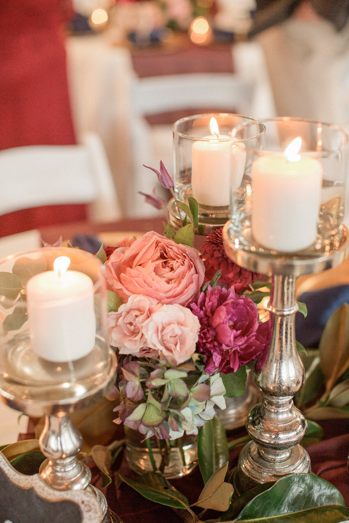 A close up of the centerpieces, featuring candles on silver candlesticks, roses, hydrangeas