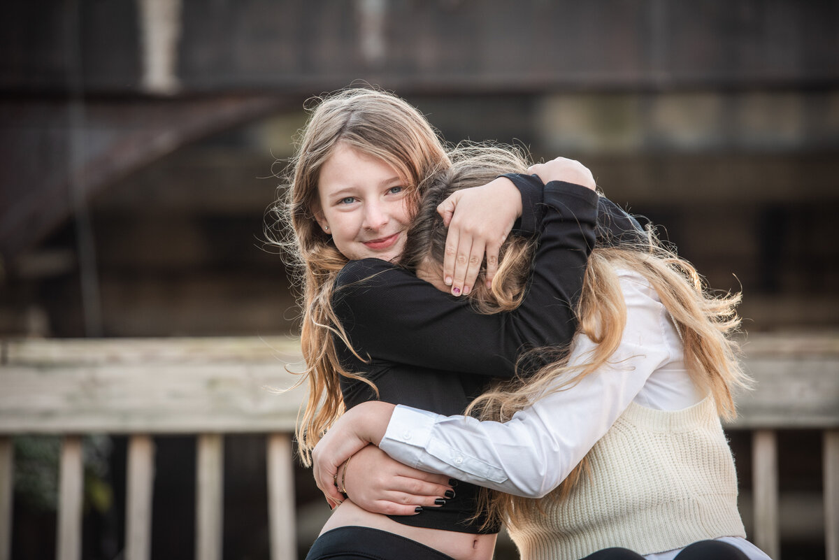 Two sisters hugging as one has their arms around the other's head
