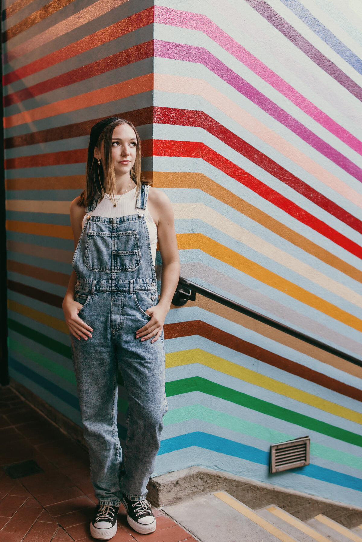 San Francisco senior portrait session at Ghiradelli Square of girl in overalls in front of mural wall
