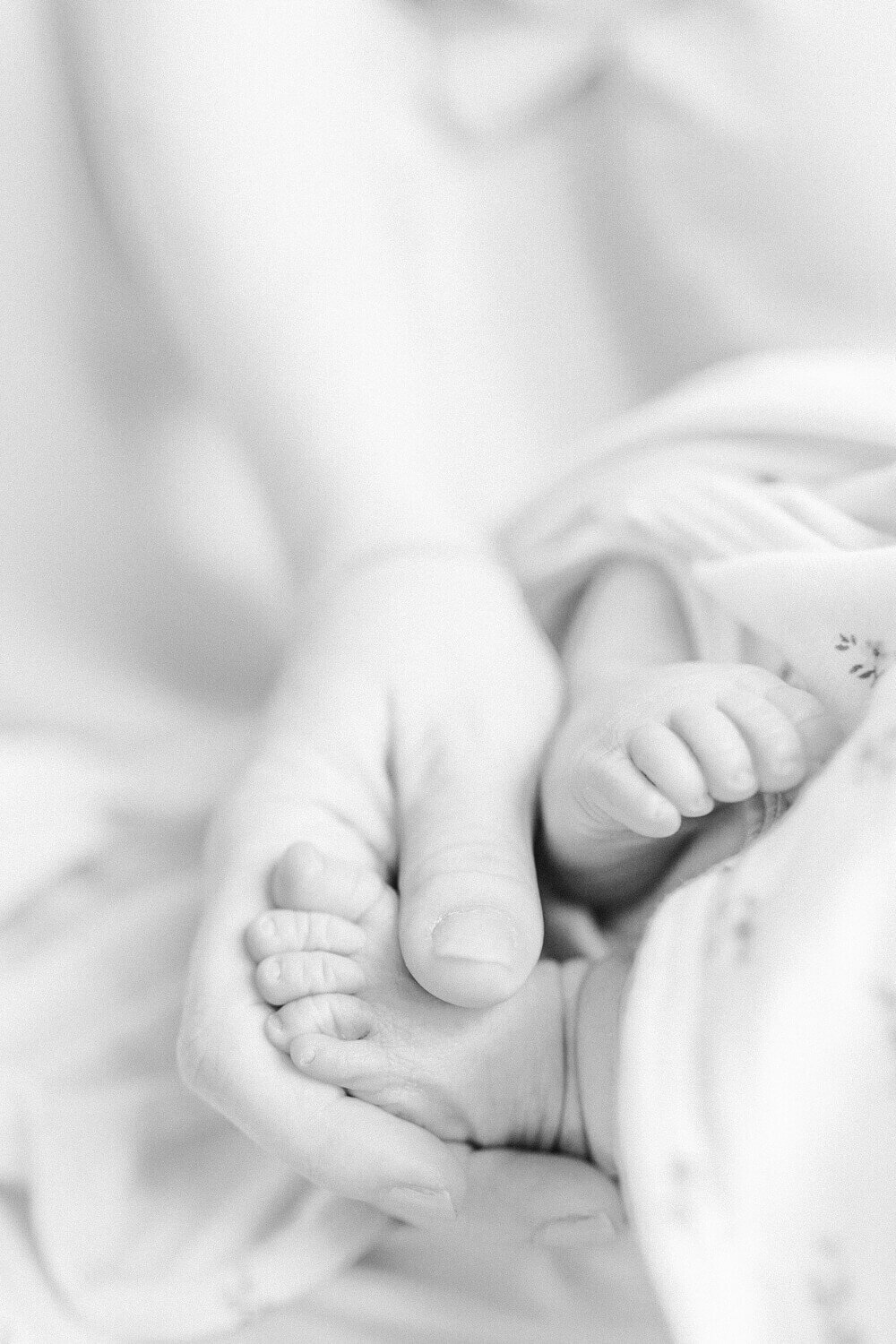 Close-up image of a mom's hand holding her newborn's foot