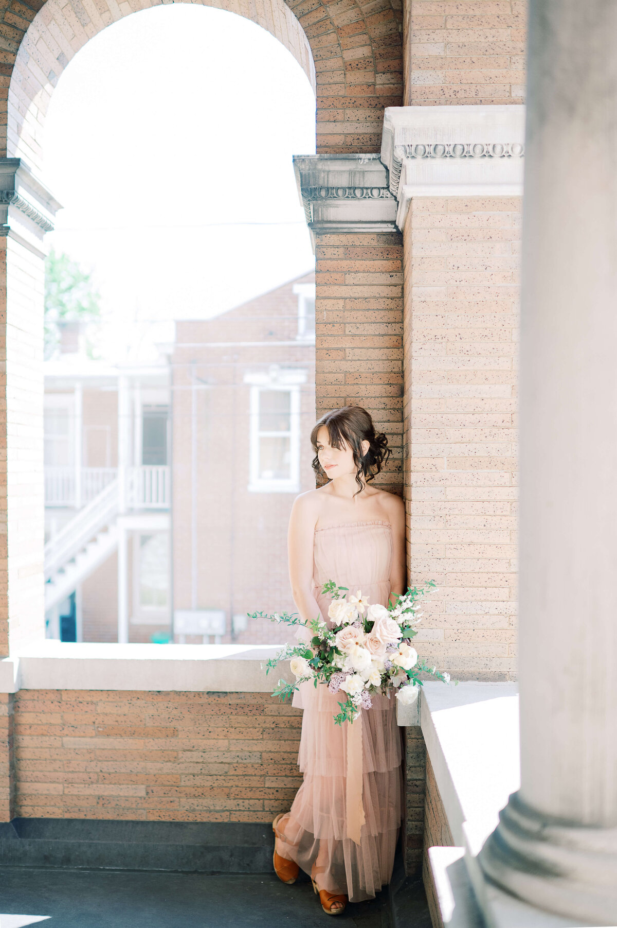 woman standing under an arch holding a bouquet