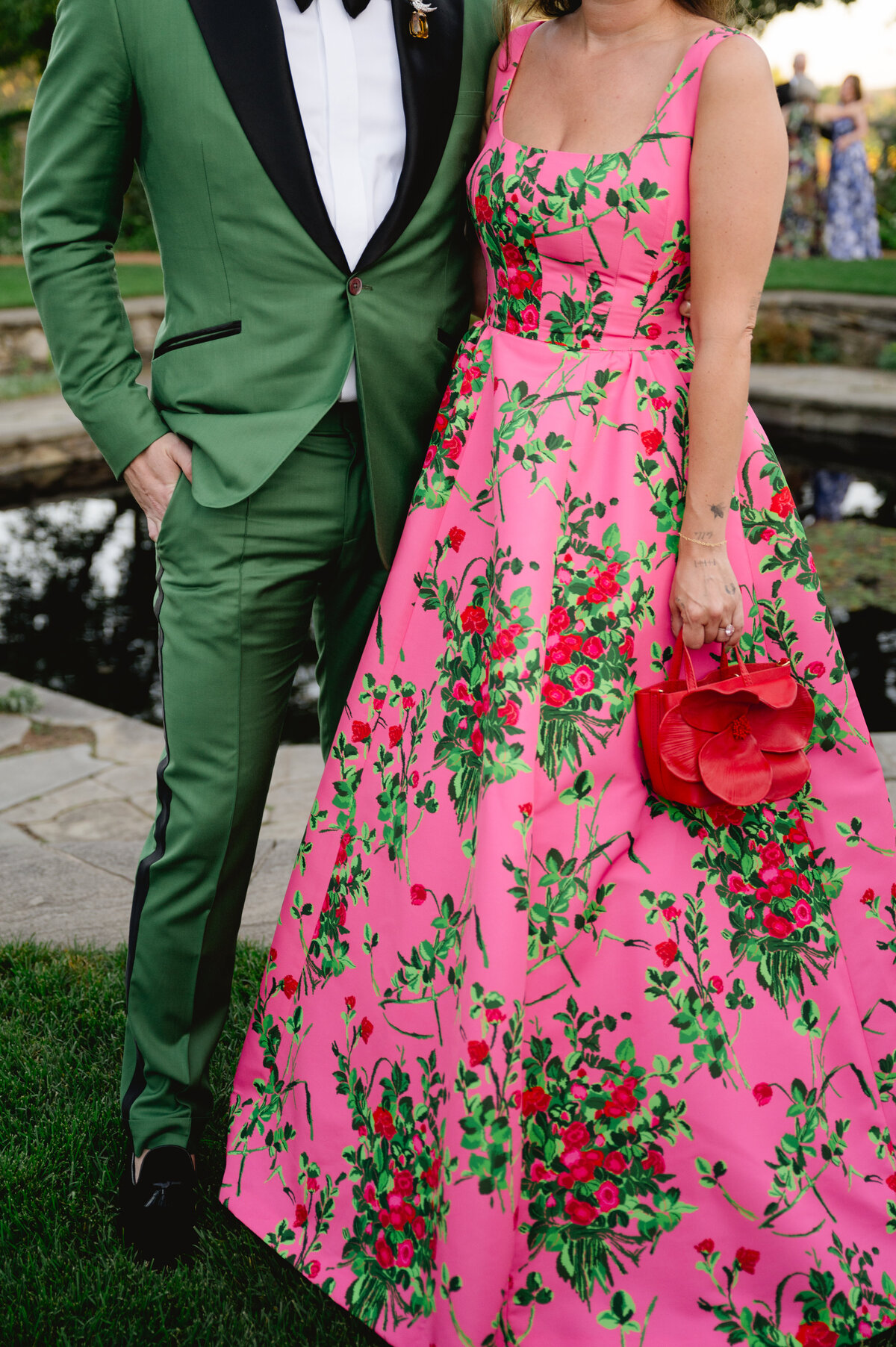 Woman in a floral pink gown holding a red flower at a wedding at the Chicago Botanic Gardens