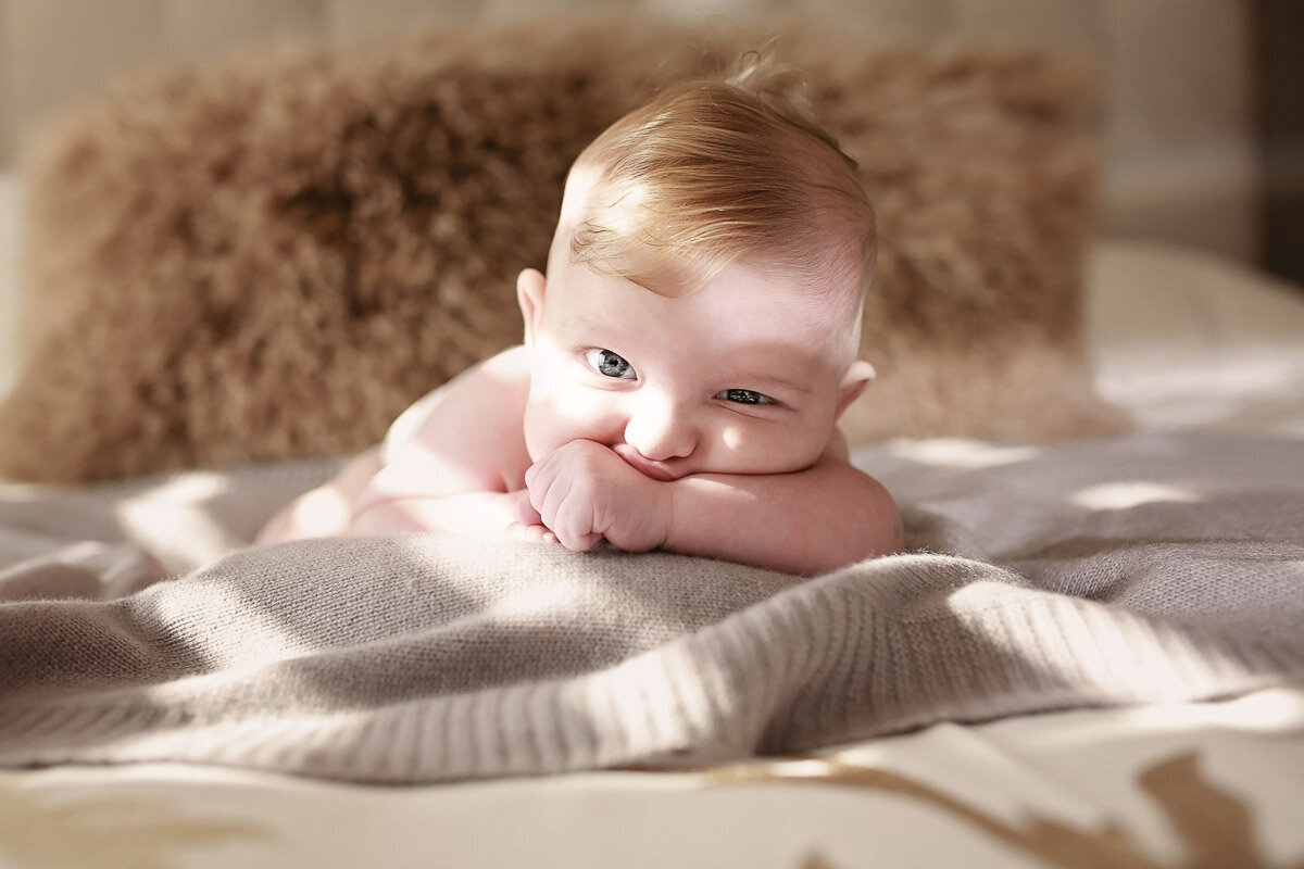 Baby laying down on his tummy with opened eye for photo session in Calgary Alberta