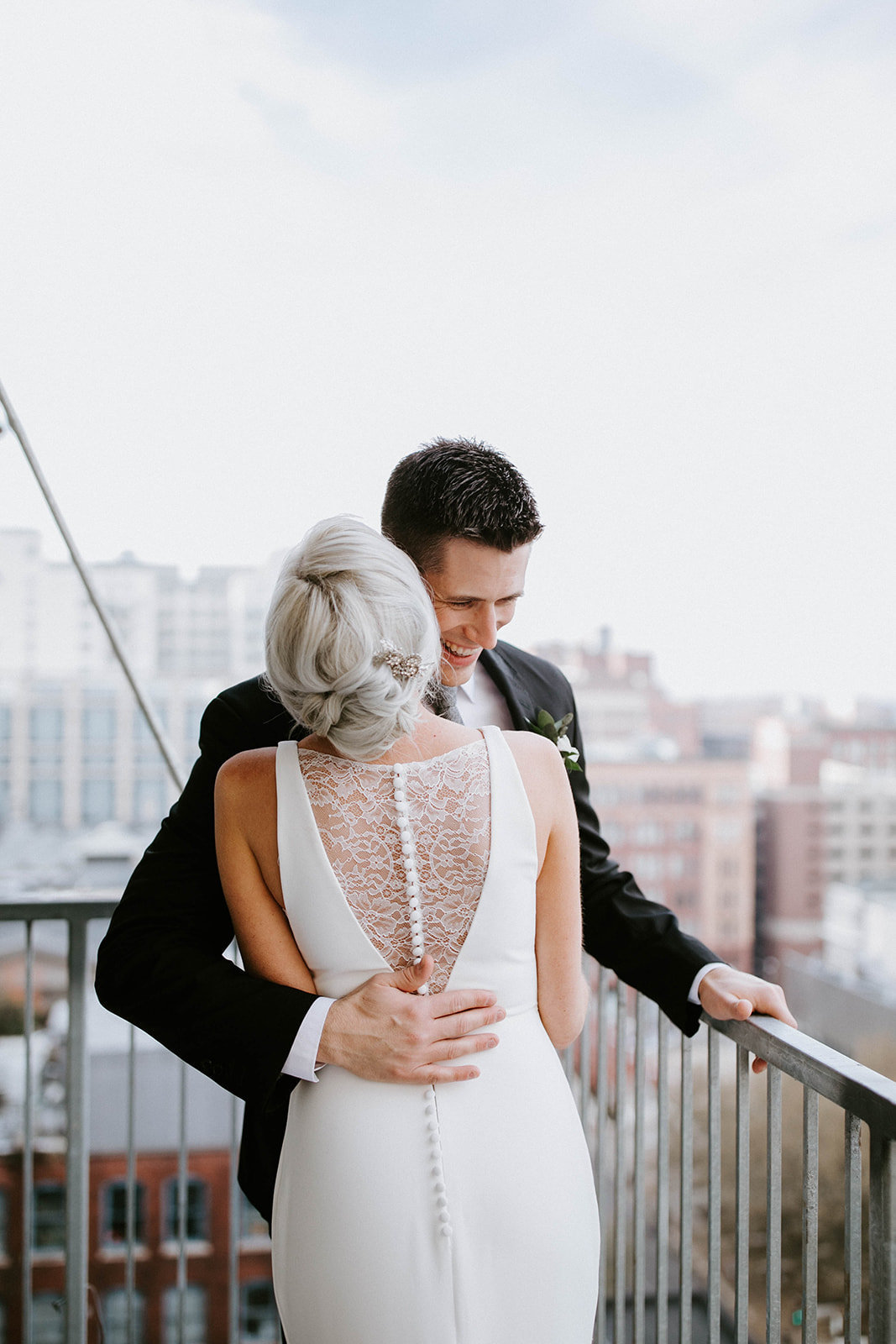 Bride and groom hug on balcony.