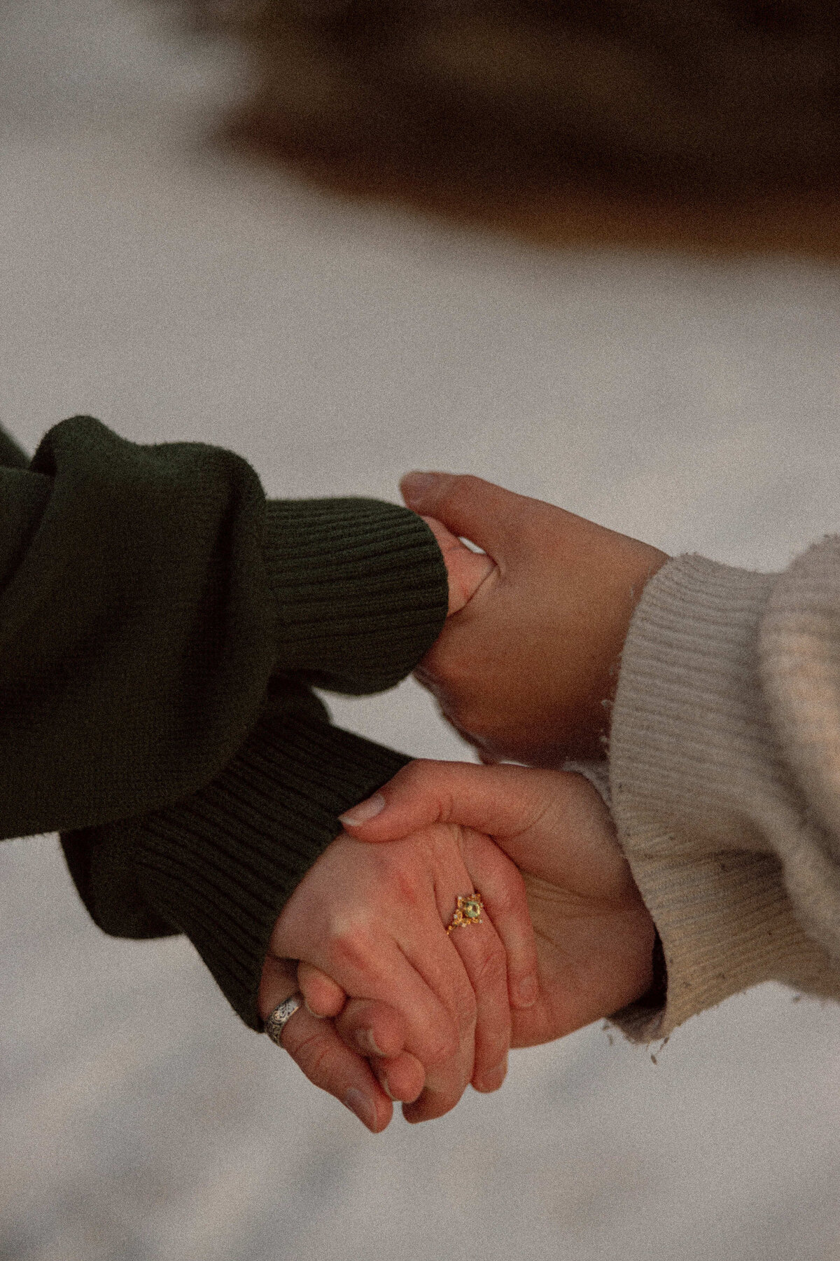 Two people holding hands showing off an engagement ring 