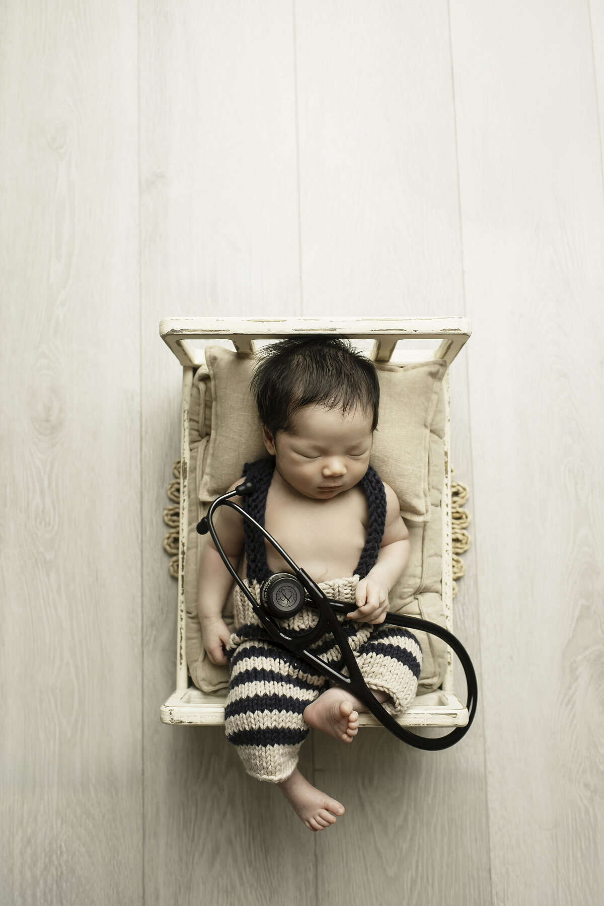 Newborn baby boy peacefully lying on a soft bed, gently touching a stethoscope, creating a heartwarming and symbolic scene