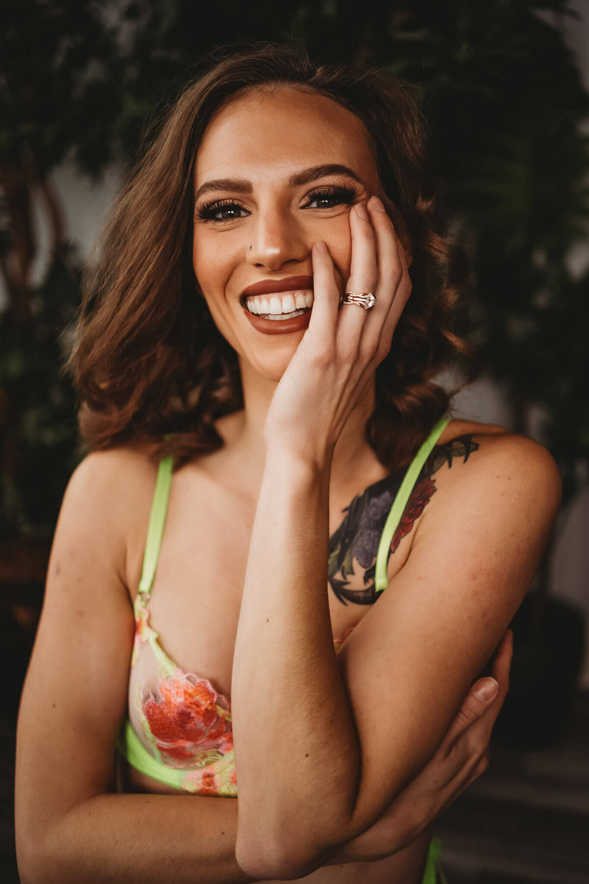 woman wearing neon lingerie smiling at camera with hand on face to show off wedding ring