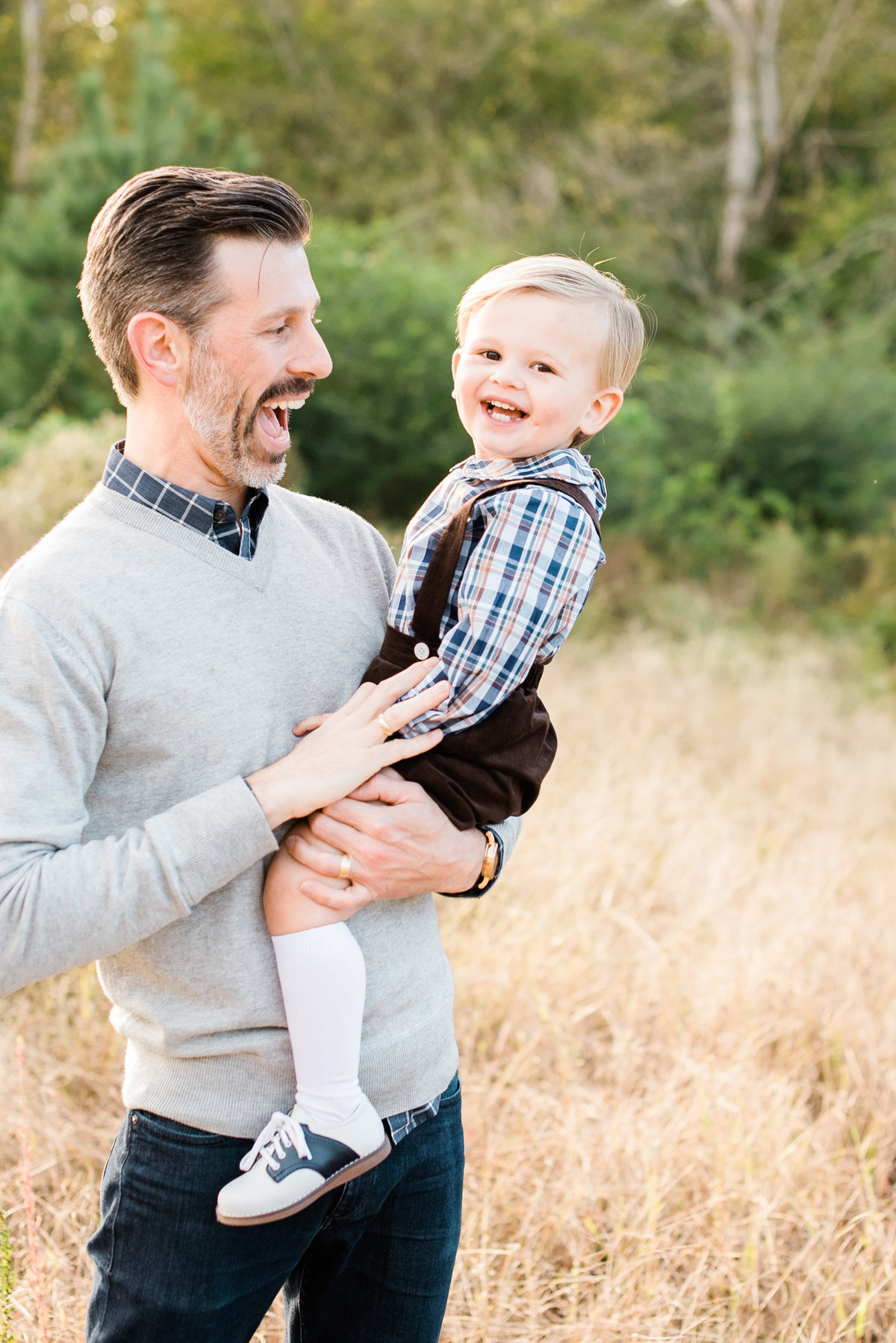Dad holds toddler son and laughs with him during a family photo session in Raleigh. Photographed by Raleigh NC Family Photographer A.J. Dunlap Photography.