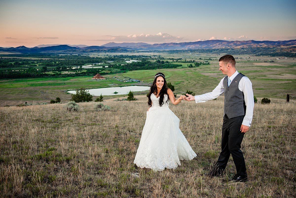 Couple dancing together in a grassy knoll with Headwaters Ranch behind them