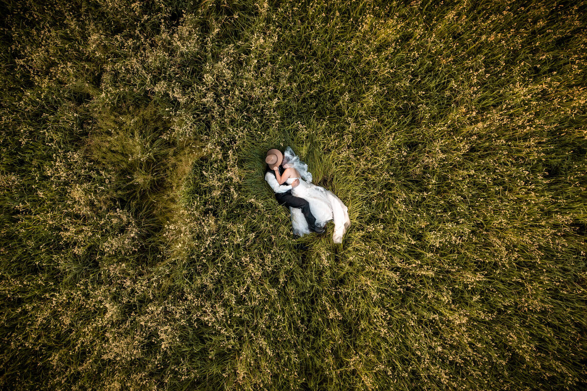 Aerial wedding photography of a couple lying together in a grass field during sunset at a wedding near Pittsburgh, PA