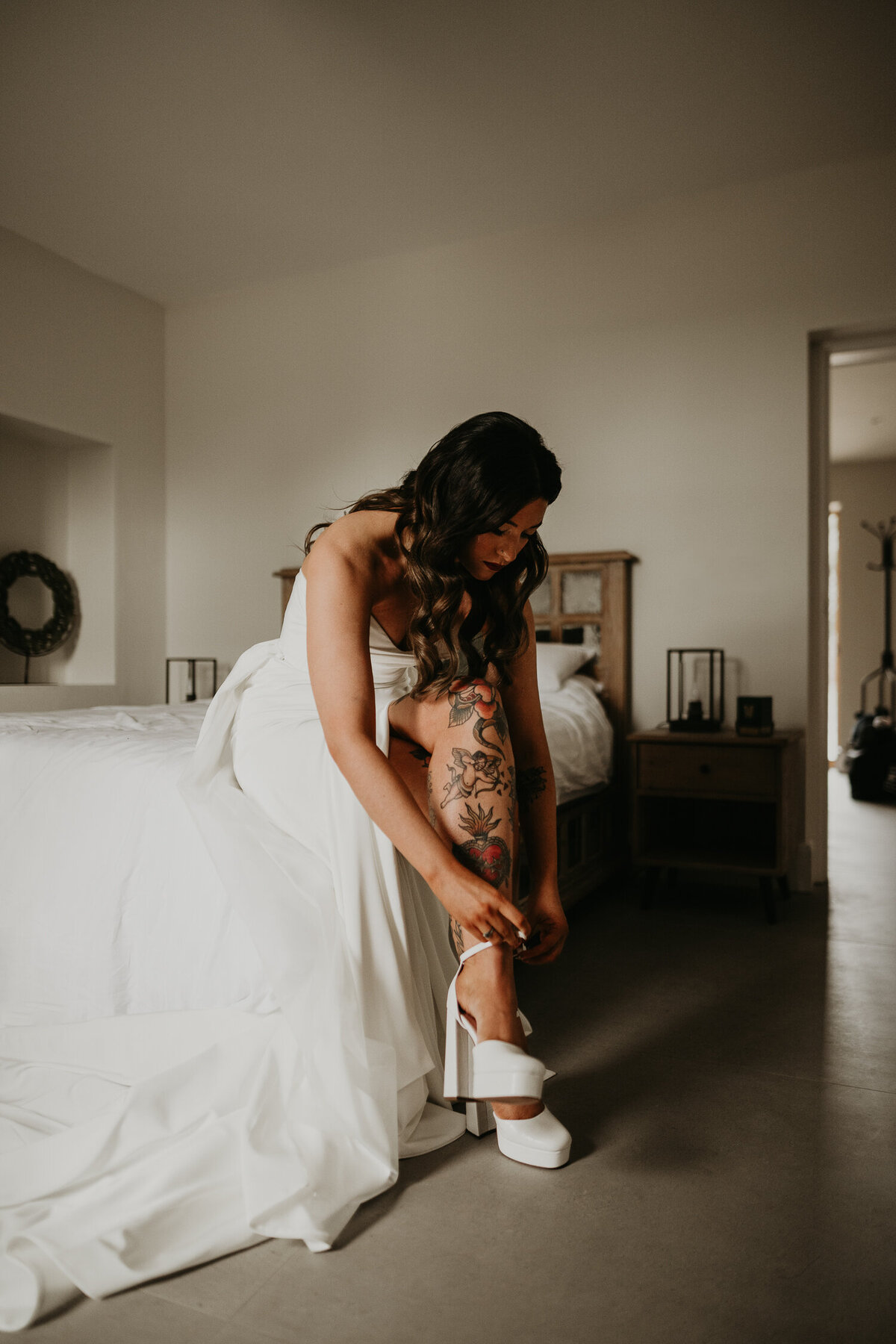 A tattooed bride puts on her wedding dress and shoes.