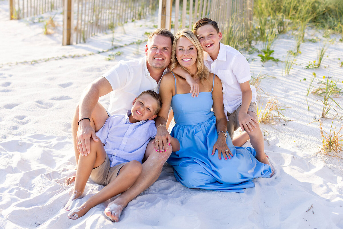 family of 4 wearing blue on the beach in front of High Pointe condos on 30a in Seacrest Florida.
