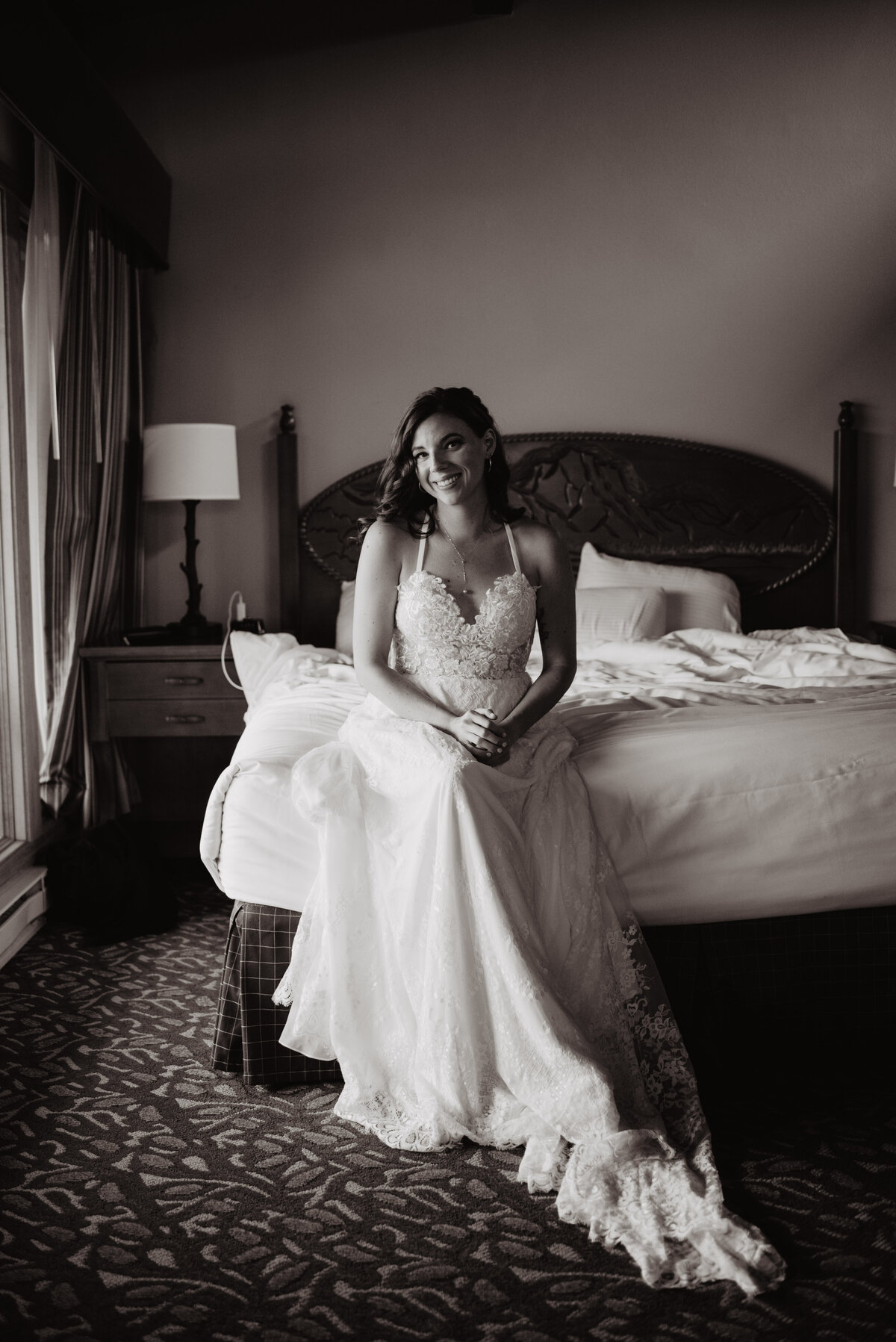Jackson Hole Photographers capture bride sitting on bed wearing wedding dress before adventure elopement