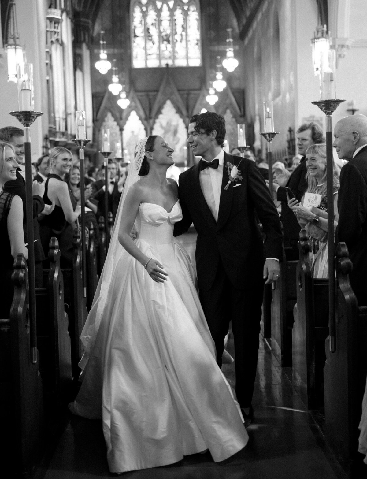 A bride and groom lean in for a kiss during their recessional among ornate historic detail at Christ Church, Detroit