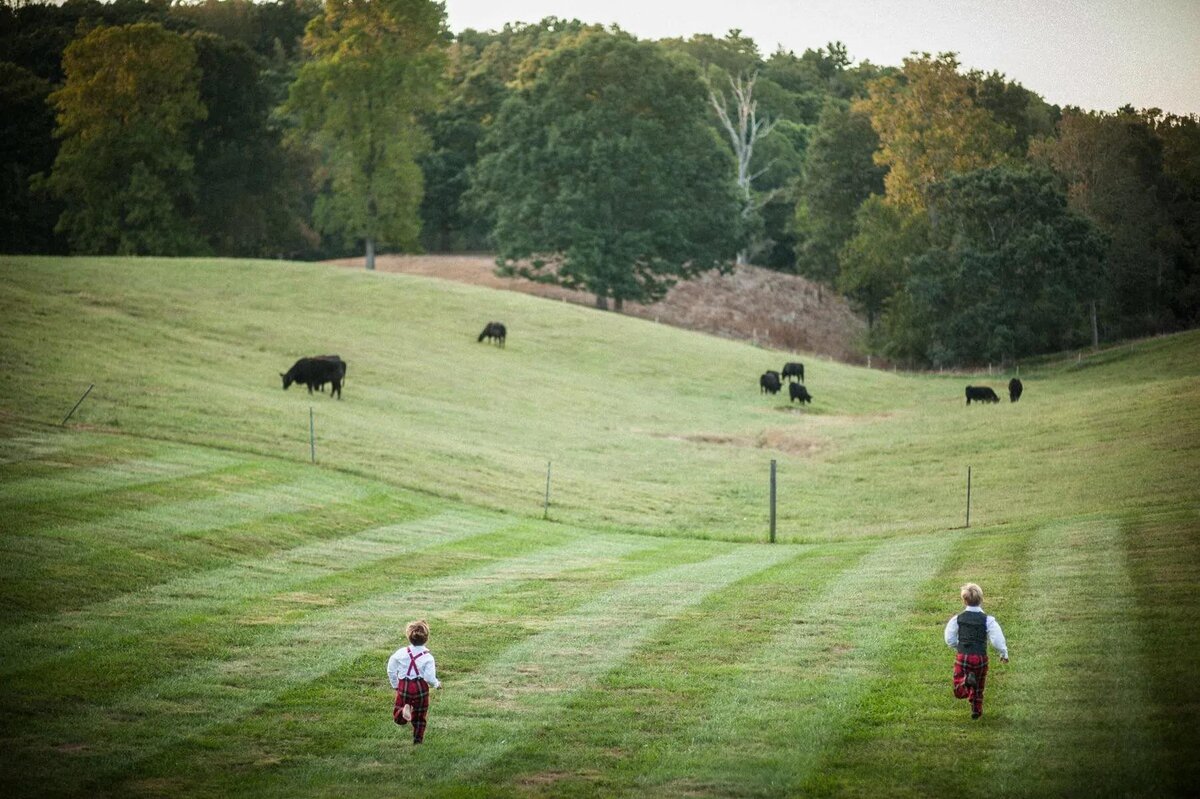 Two kids running in a large field.