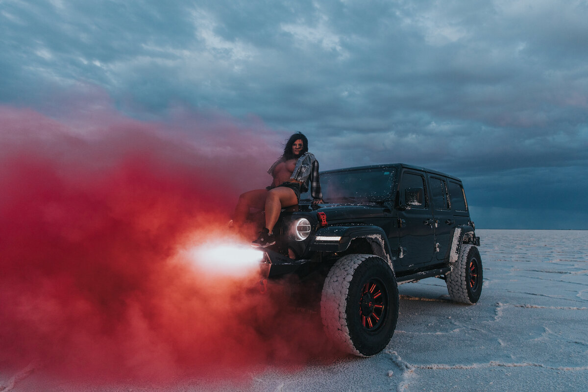 woman on top of her car with pink smoke coming out