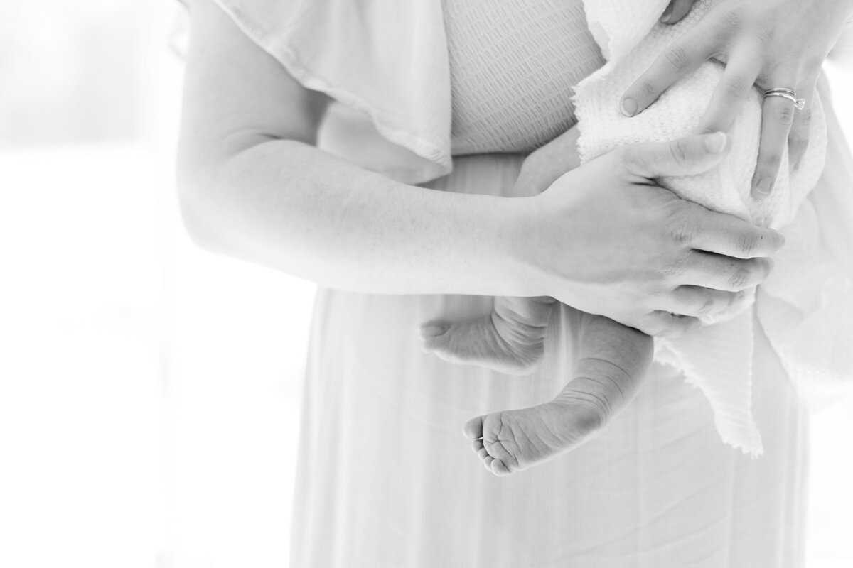 Mom holding newborn near window during soft morning light