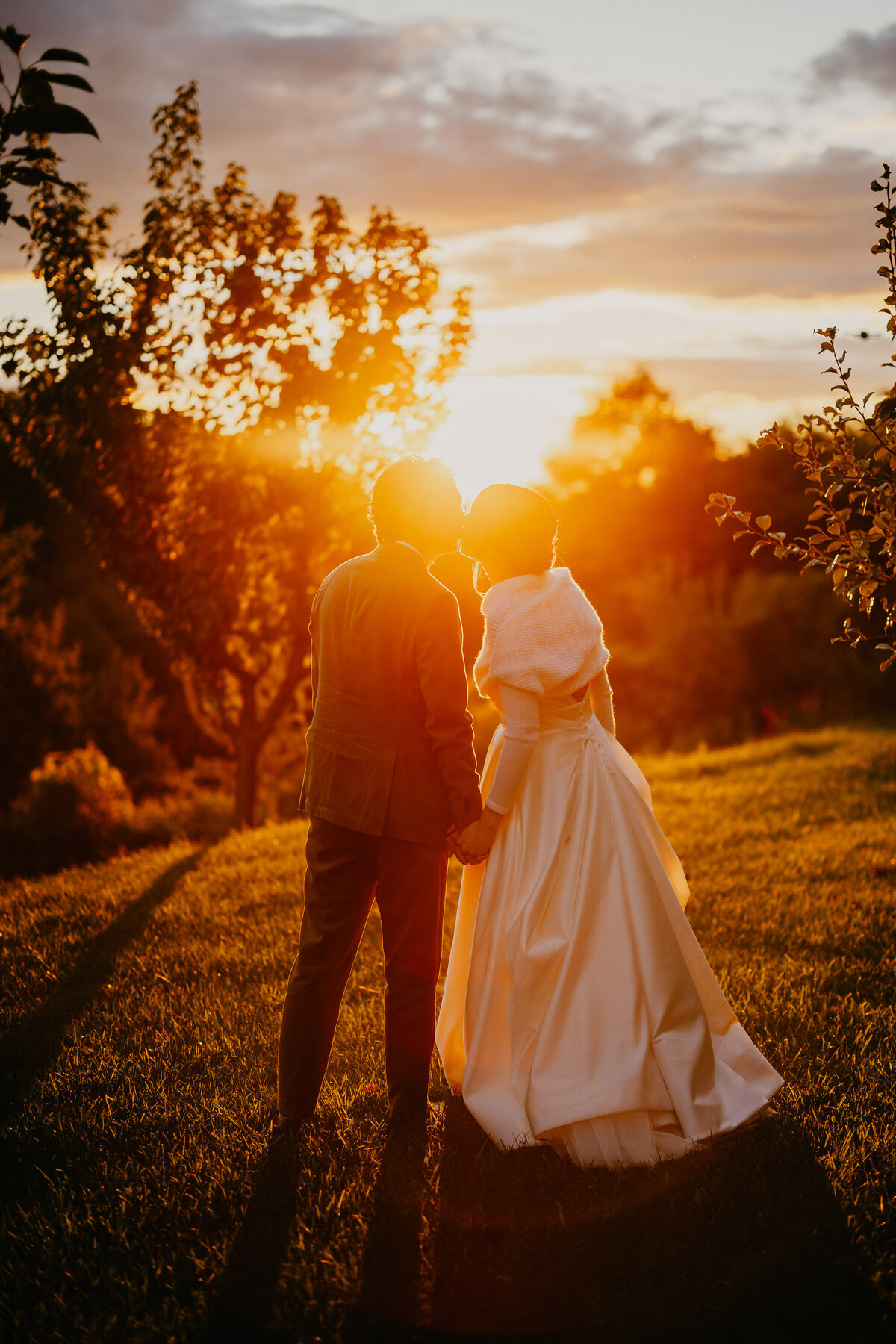 Bride and groom holding hands at romantic sunset in Montalcino countryside, wedding photographer Tuscany.
