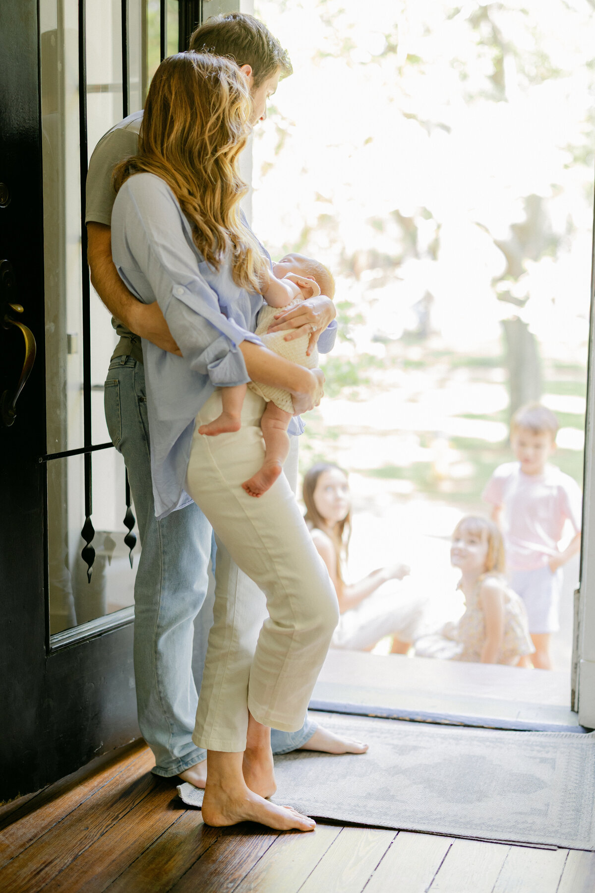 In home session of mother and father in door frame. holding their newborn baby- captured by Amy Marie Photography in Pearland, Texas. 