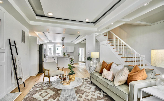 Open-concept living space featuring coffered ceilings, custom trim work, hardwood flooring, and seamless flow into a modern kitchen—designed to maximize style, comfort, and functionality.