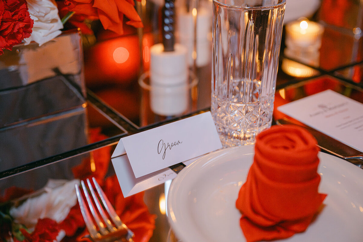 Custom name card and rose napkin atop clean mirrored place setting at luxury wedding in Texas