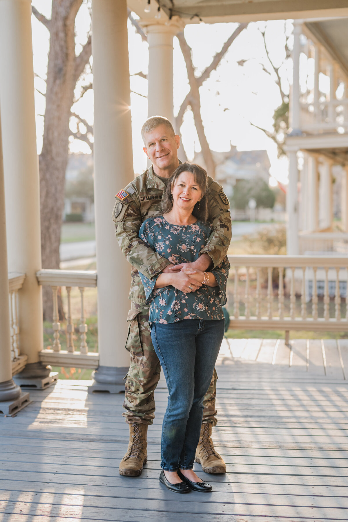 Portrait of a military couple on their front porch with the sun streaming around them.