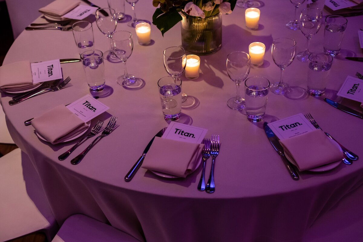 Close-up of a Titan-branded dining table with place cards, candles, and elegant settings at the New York event.