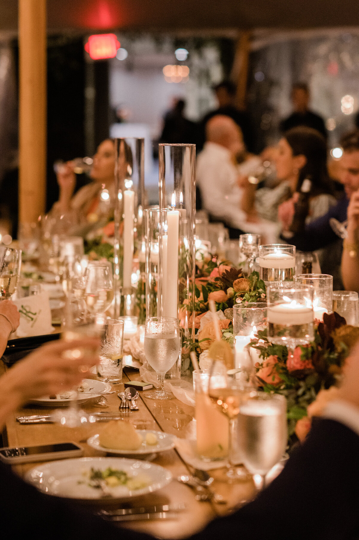 A long, candlelit dining table at Spring Lake Golf Club is covered with floral arrangements in soft pink and peach tones