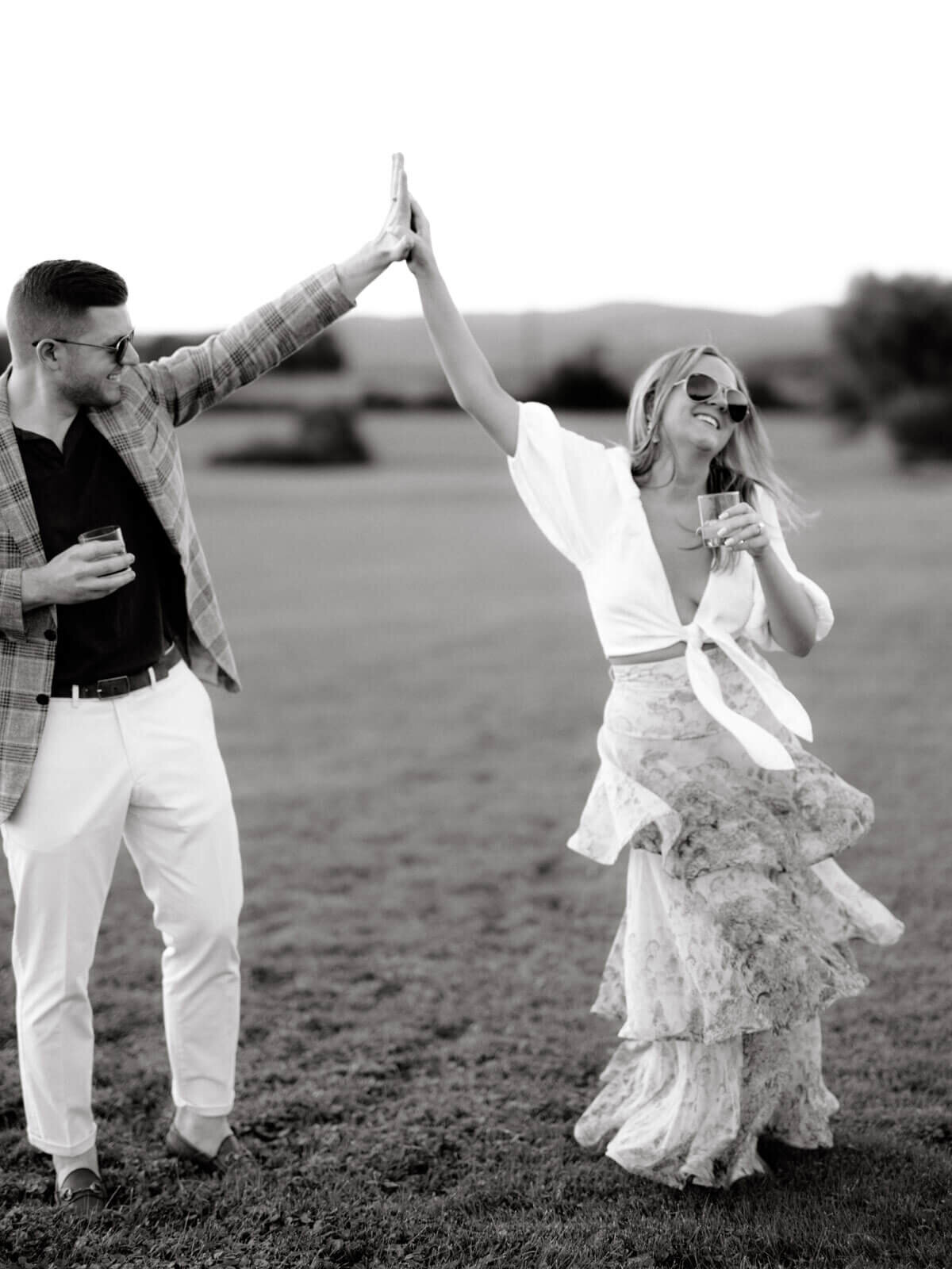 A fashionable man and woman are dancing outdoors as they drink their cocktails at Lion Rock Farms, CT. Image by Jenny Fu Studio
