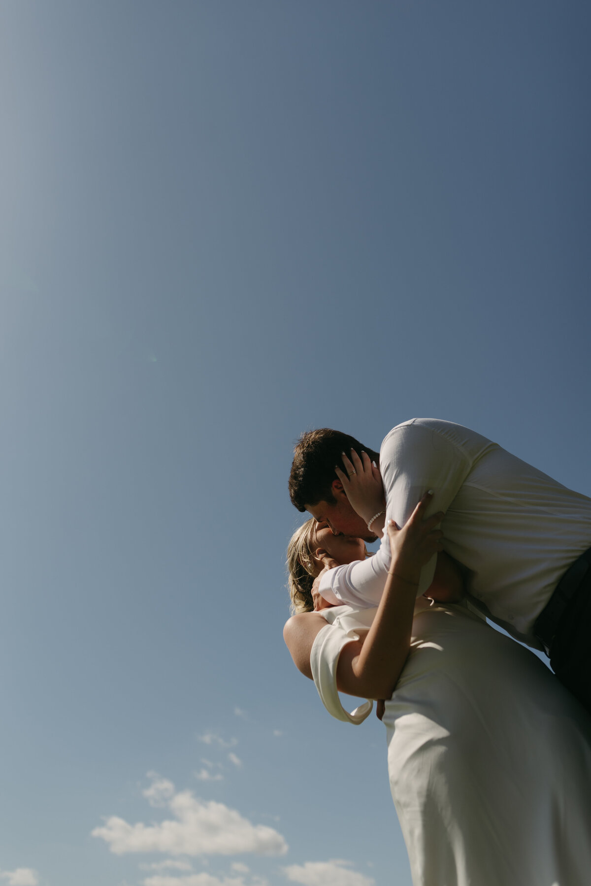 Wedding couple kissing with the blue sky as their background during their engagement session at Rip Van Winkle Gardens in Jefferson Island. 