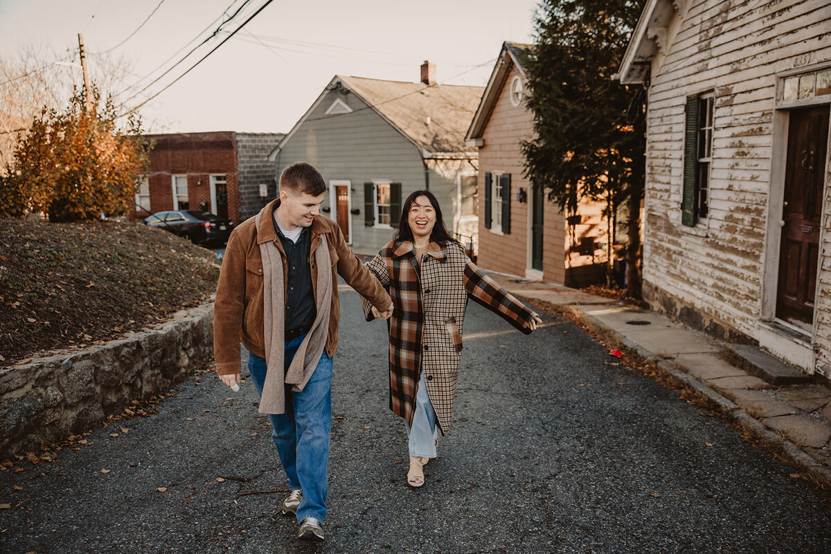 A couple holding hands and walking up a street in a small town 