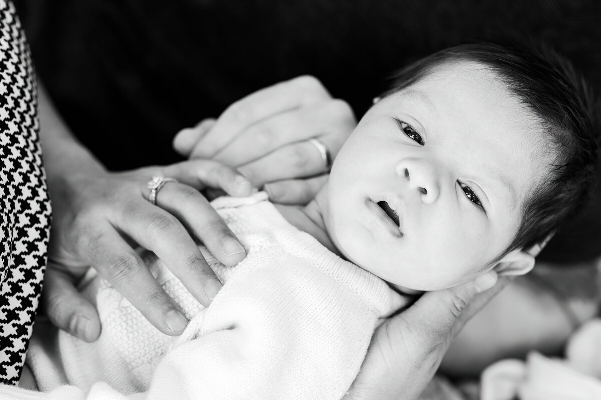 newborn looking at camera being held by mum & dad