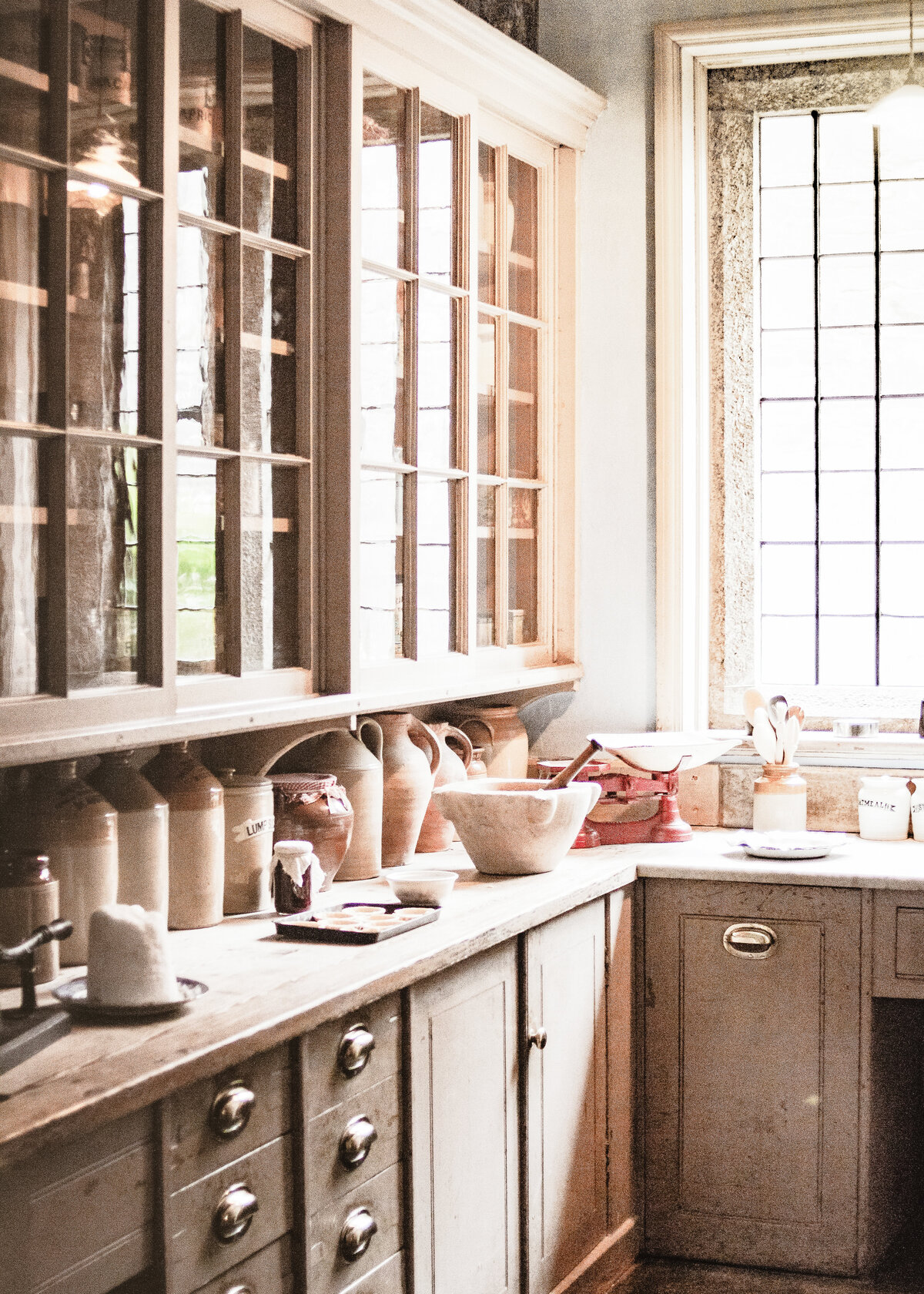 Natural wooden units hold traditional pottery milk churns in a rustic utility room.