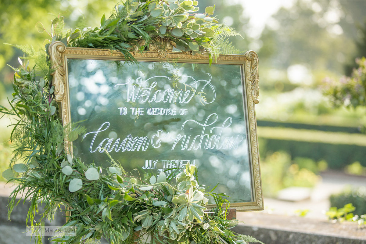 Welcome sign with greenery wrapped around it