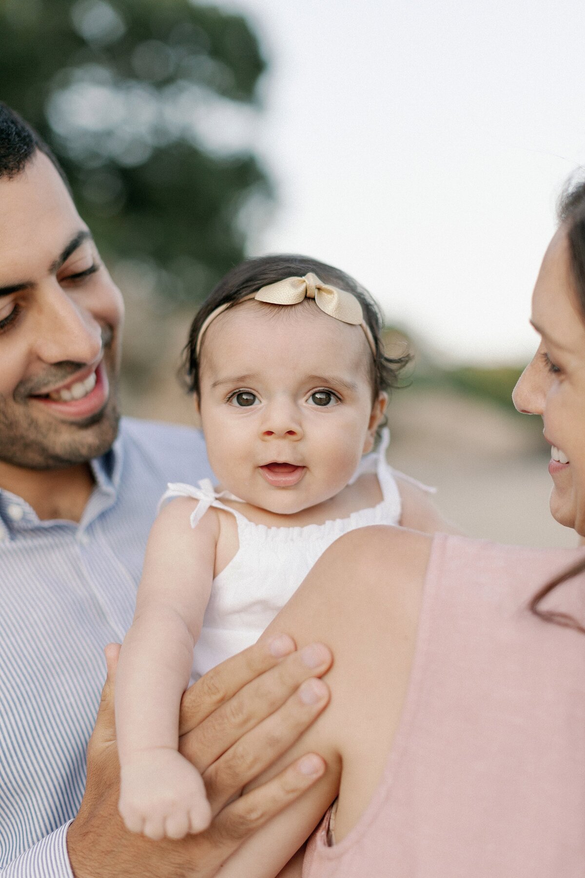 Parents hold child during portrait session at Singing Beach.