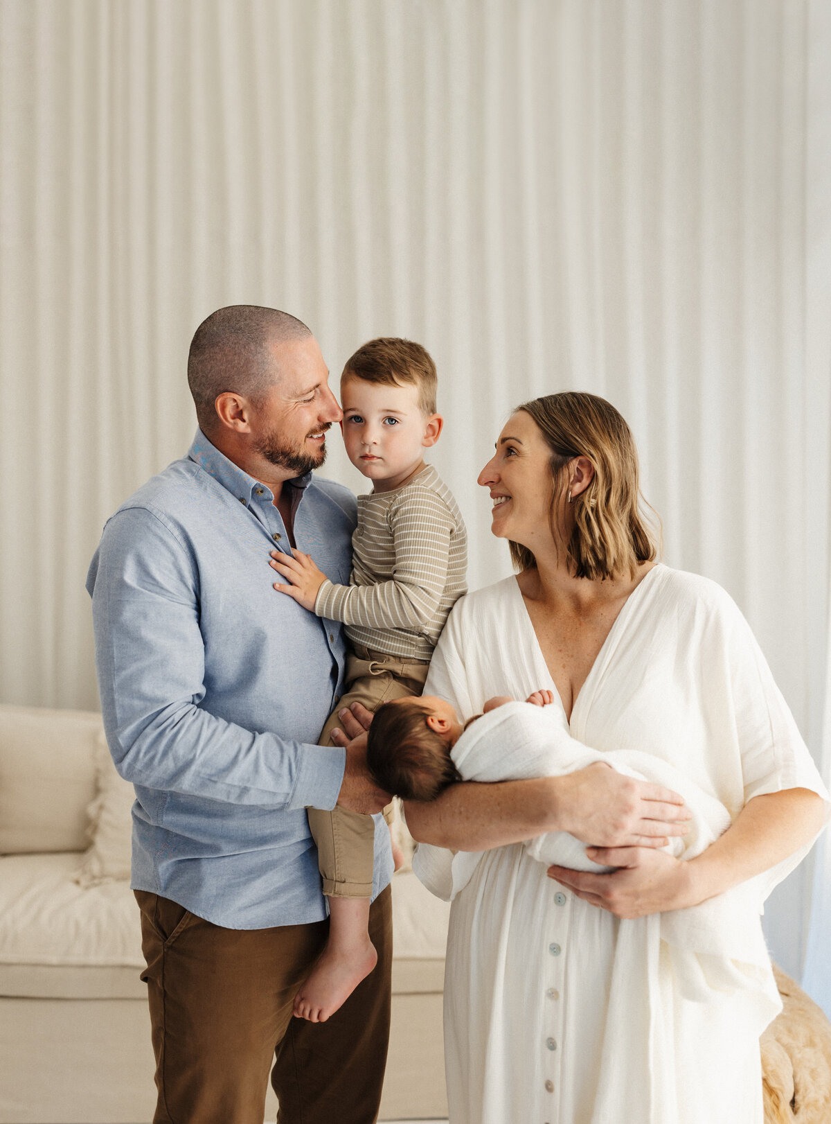 A family of four wearing whites, browns and tan during a family studio photoshoot in christchurch with lucy jane photography