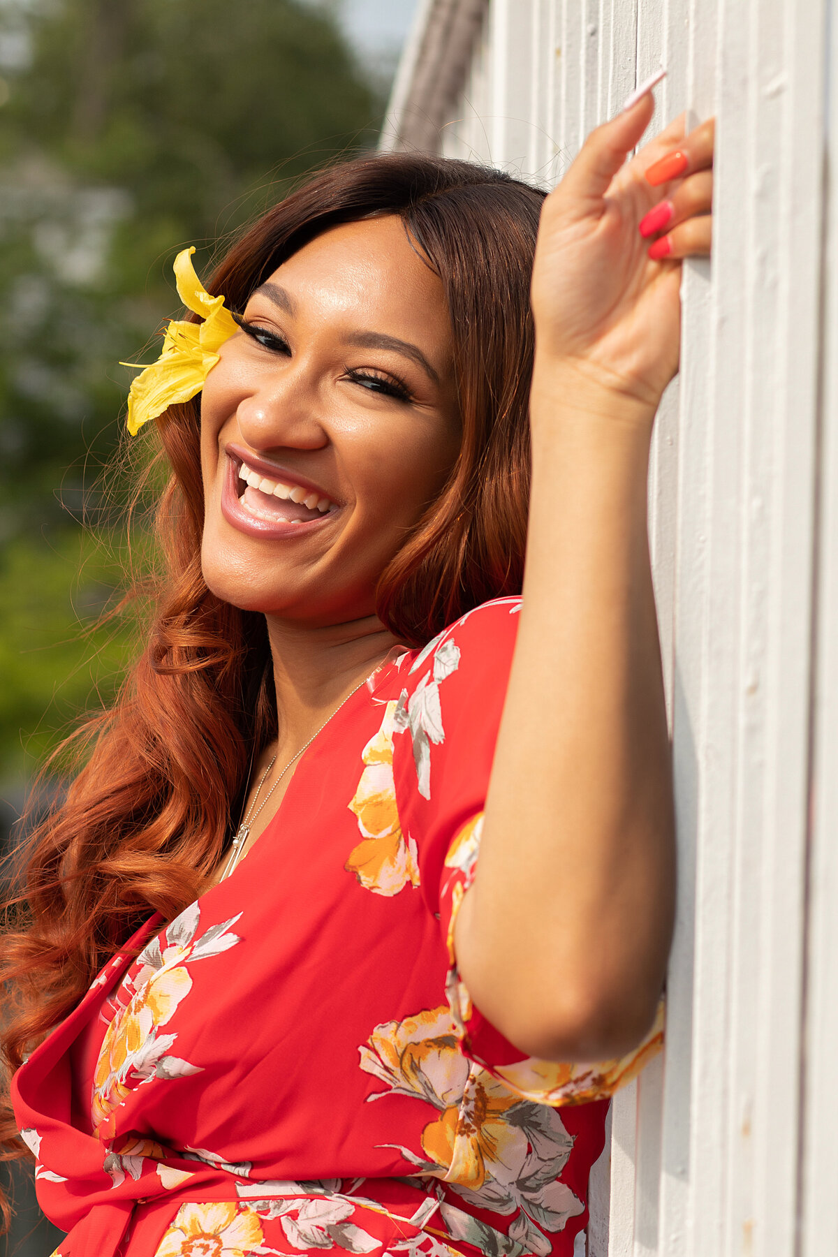African American woman in red floral dress sitting on bridge holding posts on a bridge