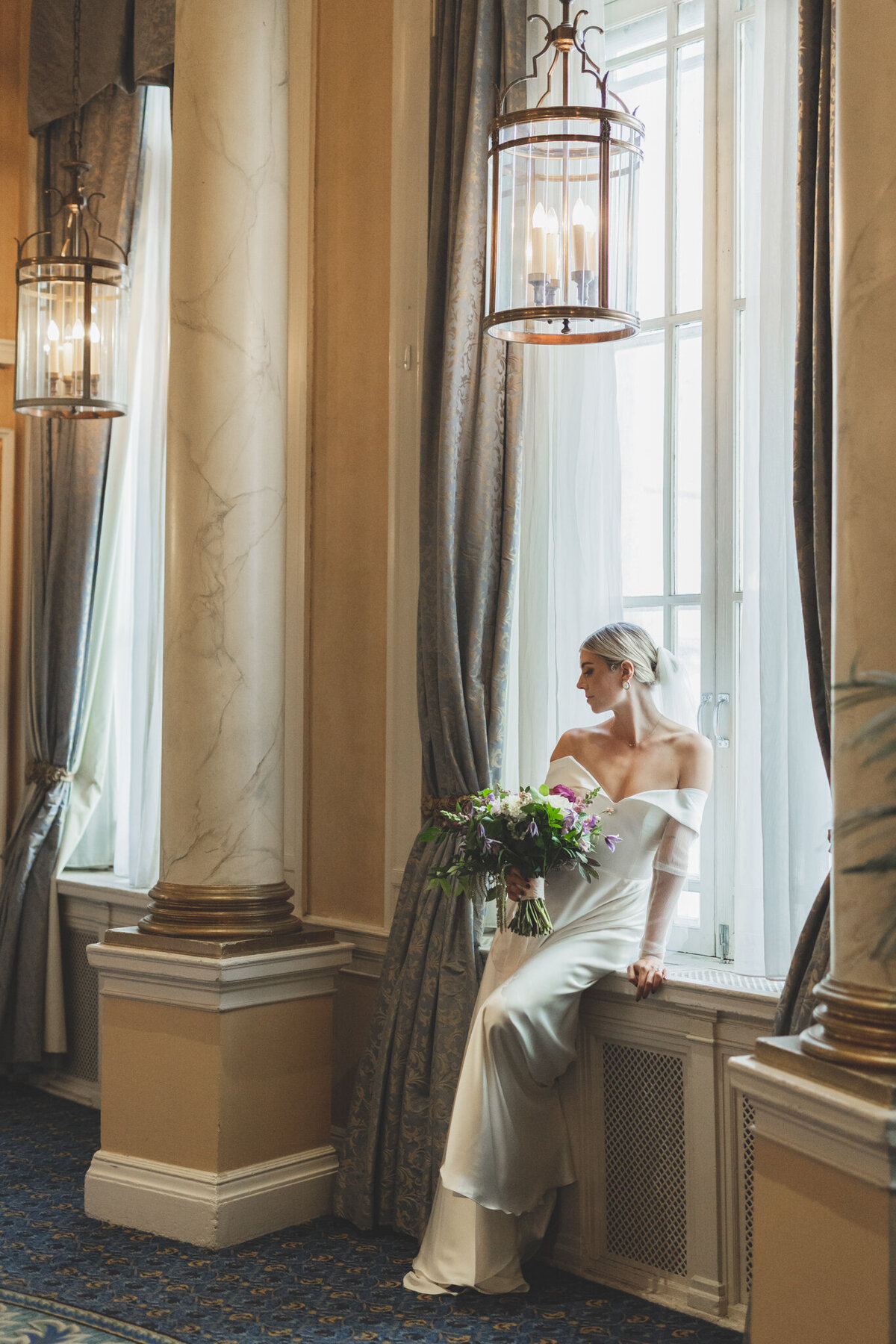 Stunning and elegant bride sitting in the historical windows at  Fairmont Palliser, featured on the Bronte Bride Vendor Guide.