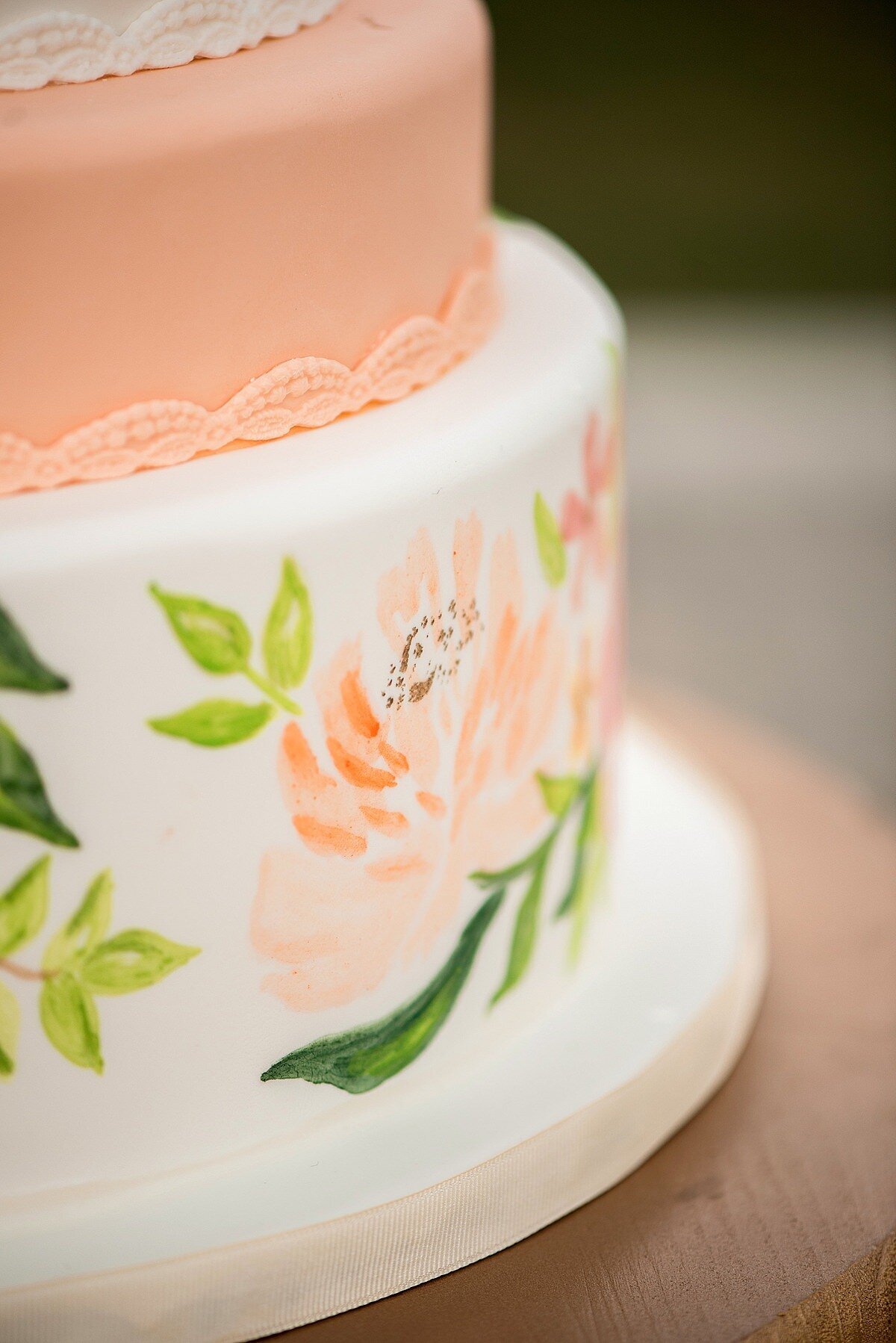 Hand painted wedding cake with peach peonies and green leaves water colored on fondant.