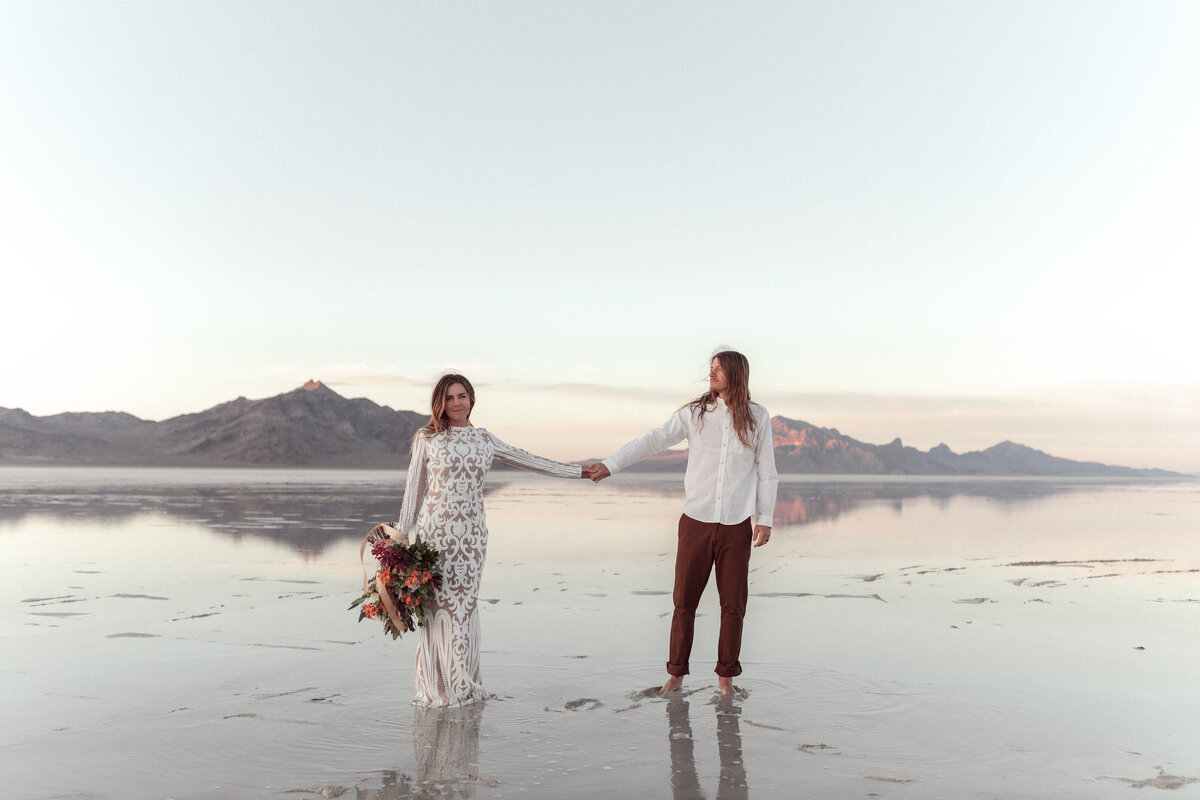 bride and groom holding hands on beach