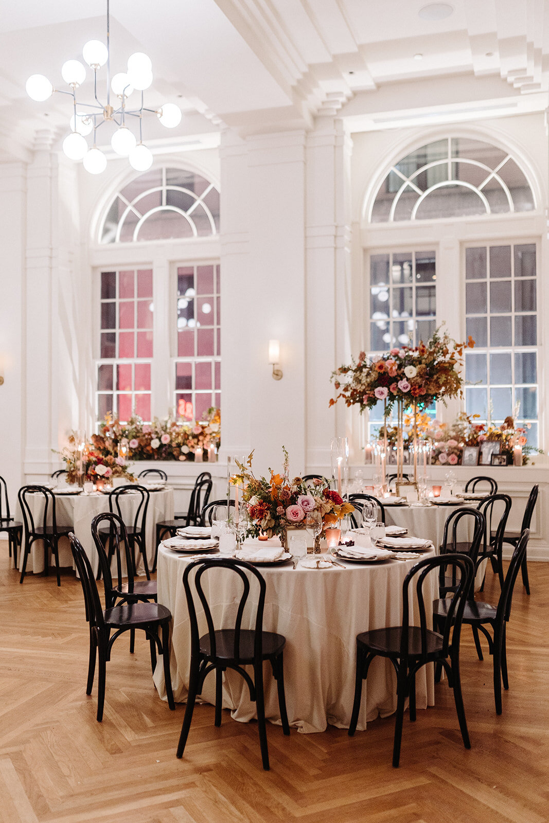 Organic floral centerpieces decorate this autumnal Parisian inspired wedding reception in hues of dusty rose, burgundy, terra cotta, and lavender composed of roses, ranunculus, delphinium, lisianthus, copper beech, and fall foliage. Design by Rosemary and Finch in Nashville, TN.