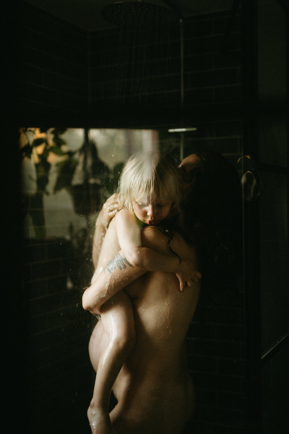 En gravid mamma tittar på när sonen och pappan till sonen leker tillsammans. Gravidfotografering Göteborg.