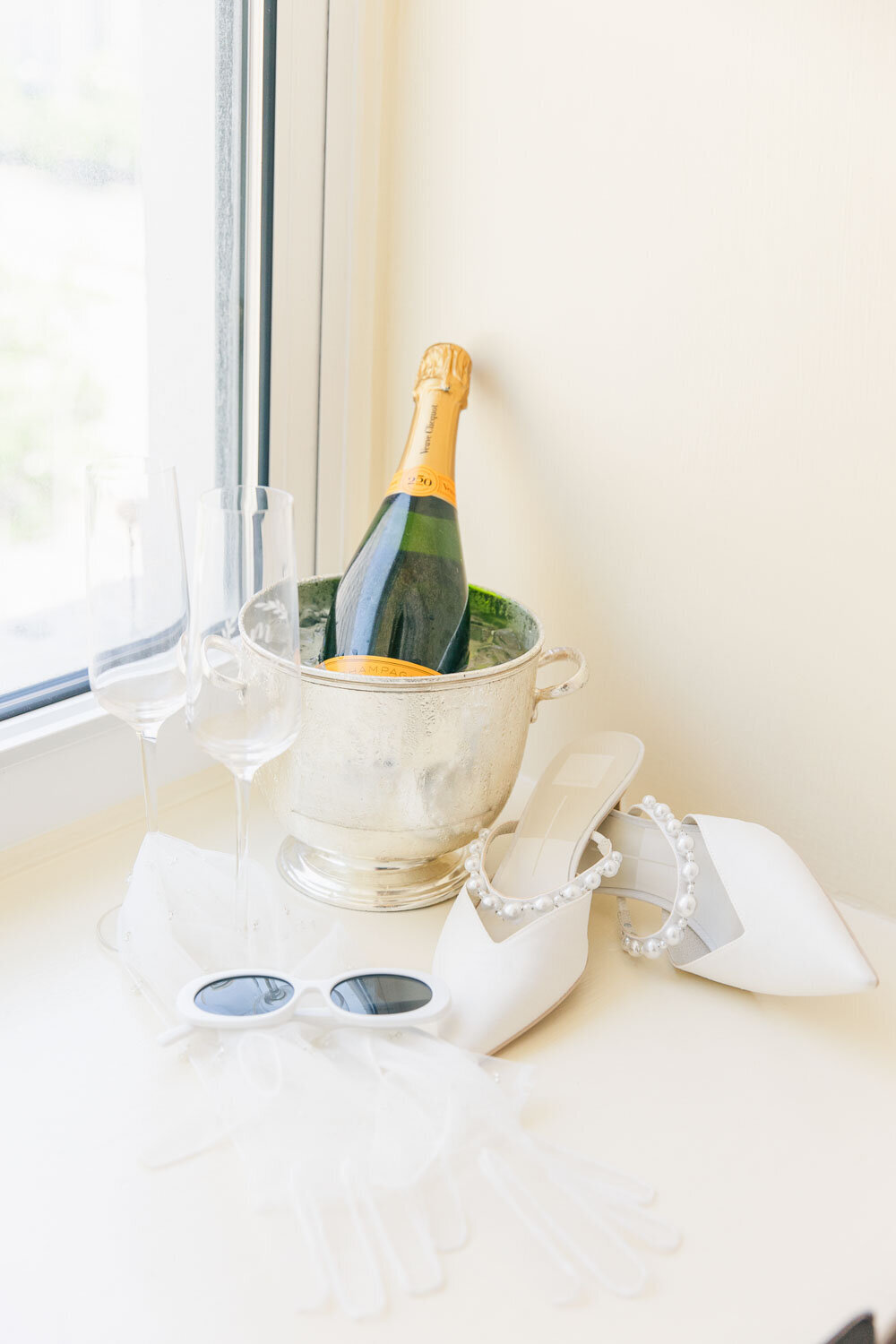 Wedding detail shot with champagne bottle, glasses, and bridal shoes