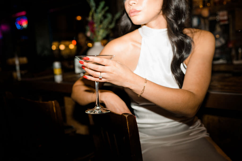 bride holding a martini glass while sitting at a bar