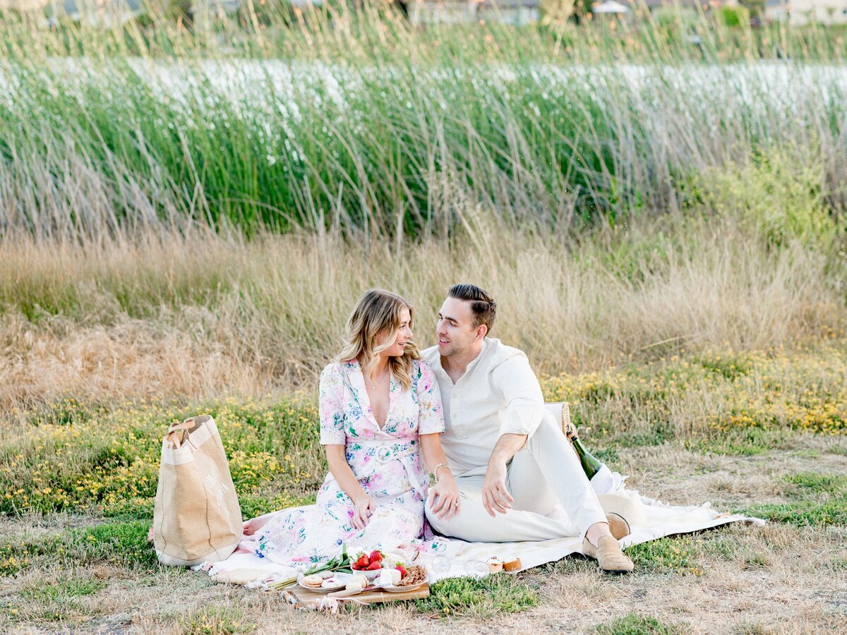 Couple sitting on blanket enjoying picnic in grassy field